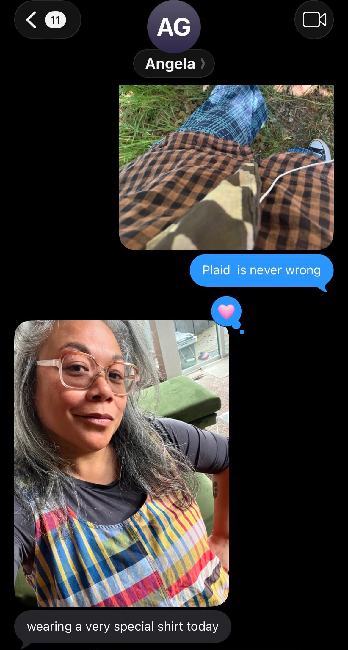 A screenshot of a text thread shows one photo of a plaid shirt worn over plaid pants and converse shoes and the words "Plaid is never wrong". Another message is a photo of a Filippina woman with gray hair and glasses posing for a selfie wearing a rainbow plaid tank top over a black shirt and the text: "wearing a very special shirt today" on black background.